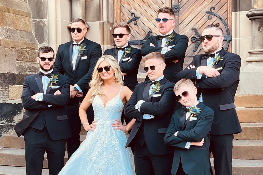 Bride and groomsmen wearing sunglasses on steps outside venue